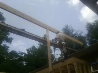 Carpenter setting a ridge beam over a new addition frame — Ice Dam Removal by Roofing Brothers in Ethridge