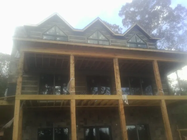 Dormers and porch framing on a large log home under construction — Roof Coating work by our crew in Ethridge