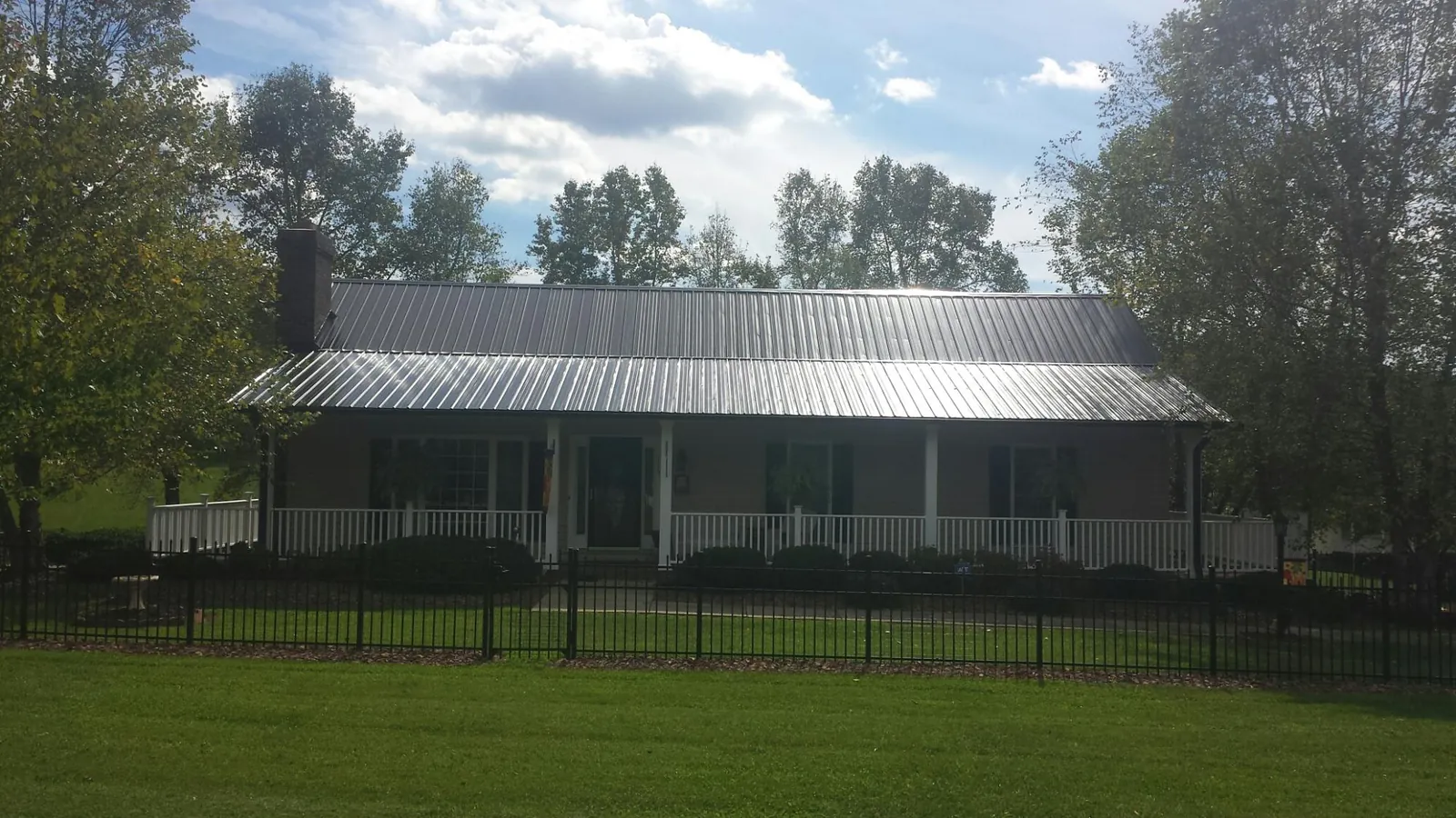 Gray metal roof on a brick ranch with a full width front porch in Ethridge