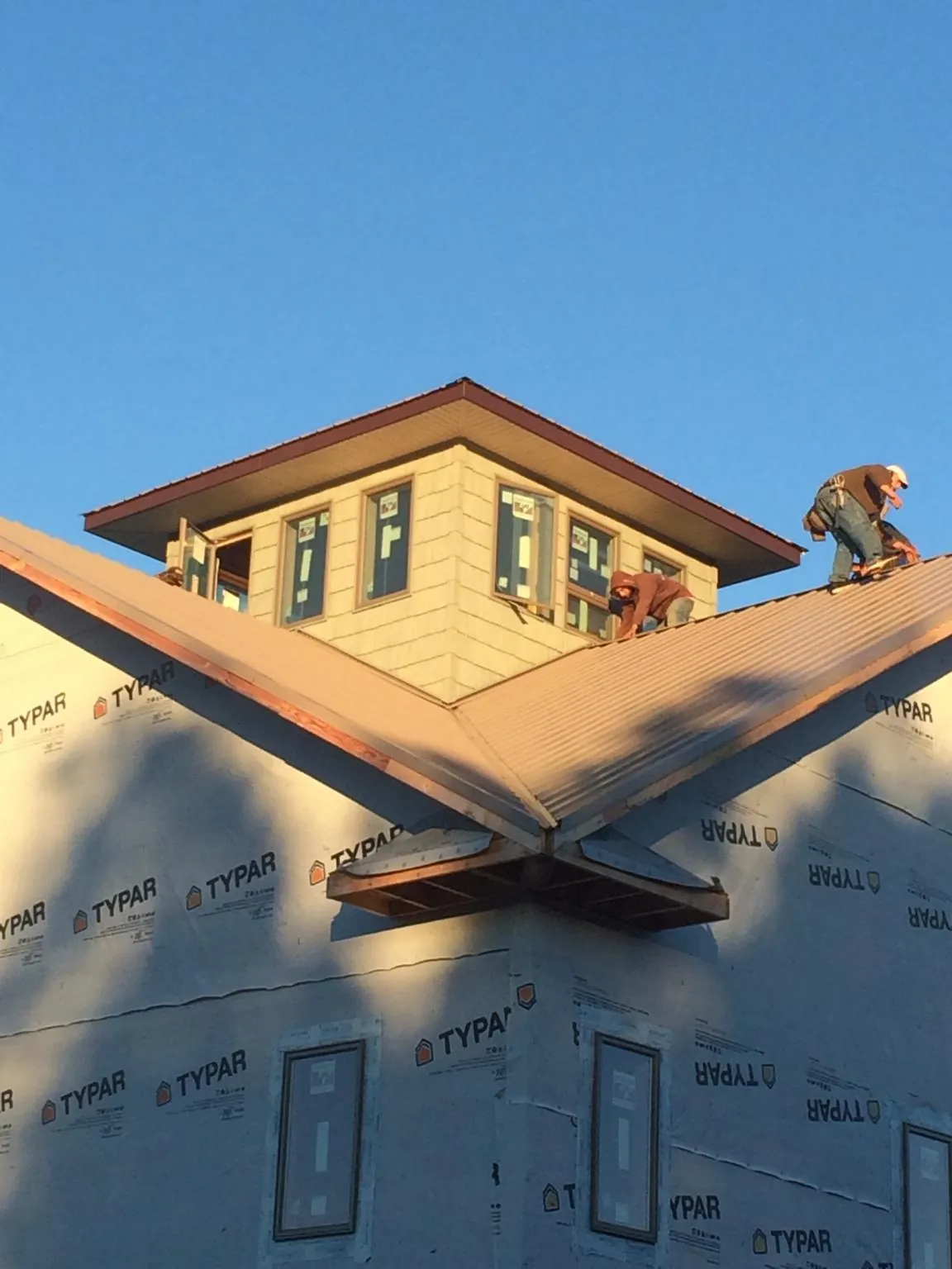 Roofers working around a rooftop cupola on a new metal roof at sunset — Roof Waterproofing in Ethridge by Roofing Brothers